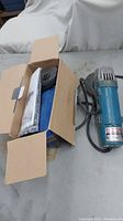 4" Makita grinder next to an open box containing accessories or manuals