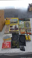 Overview photo of assorted vintage train accessories laid out including building kits, landscaping bags, glue bottles and track sections.