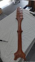 Full length view of the wooden native art paddle on a white cloth background showing the handle and blade shape.