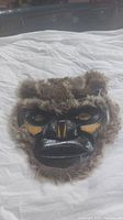 Full view of the wolf mask showing fur trim, carved wooden face with dark finish and detailed expressive features.