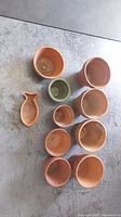 Photo of 10 terra cotta plant pots and 2 small fish-shaped dishes taken from above showing sizes and condition