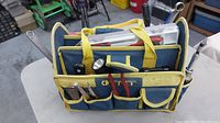 Full view of the tool carry bag with a variety of hand tools inside and pockets on the outside.