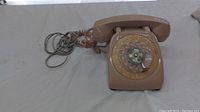Full view of the brown vintage rotary dial telephone showing handset, coiled cord, and overall condition