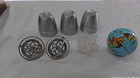 Photo showing three metal cups, two metal string top spinners, transparent geometric star puzzle, and puzzle globe.