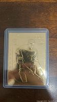 Front of Wayne Gretzky gold-plated hockey card showing embossed player image and name, in clear plastic holder.