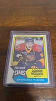Photo showing a 2014 Hot Shot Prospects hockey card of Connor McDavid in a protective plastic case.