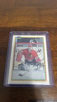 Photo of Ed Belfour rookie hockey card in protective sleeve on wood surface.