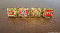 Four Buffalo Bills AFC Champions replica rings arranged side-by-side on a surface showing front face designs.