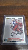 Keith Tkachuk World Junior Tournament rookie hockey card photo showing front of card in protective plastic sleeve on wood surface.