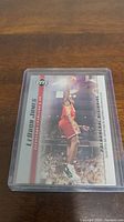 Photo of a LeBron James rookie basketball card featuring him in a red Cavaliers jersey, encased in protective plastic.