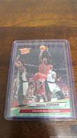 Photo of Michael Jordan Fleer Ultra basketball card in plastic sleeve showing mid-jump shot pose with Chicago Bulls uniform.