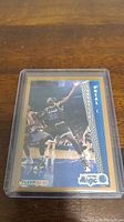 Front of Shaquille O'Neal Fleer rookie card in protective case on wooden surface