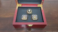 Photo of three replica Stanley Cup rings arranged in a red display box with black lining showing the front view of the rings.