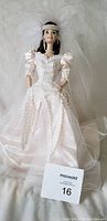 Porcelain Barbie doll standing, dressed in white wedding gown with lace, puff sleeves, pearl jewelry, and beaded headband.