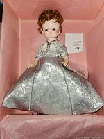 Front view of Madame Alexander First Lady Doll dressed in silver brocade gown, displayed in box.