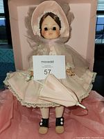 Front view of Madame Alexander First Lady doll standing with parasol, dressed in pink with lace trim and bonnet.