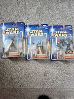 Photo shows three Star Wars Attack Of The Clones action figures new in blister packaging. Characters visible: Geonosian Warrior, Oom Fire Tail, Super Battle Droid.