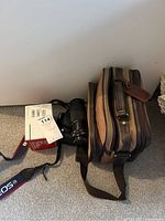 Setup with Canon EOS Rebel X camera and 17-85mm lens, KS Super II film camera, gear bag, and straps on floor against white wall