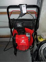 Front view of mower showing handle, engine cover, and attached grass bag