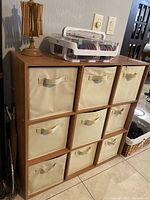 Wooden cubby shelf with beige fabric drawers organizing yarn and tools