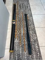 Several bamboo fly rod sections laid out with a hard tube case and a cloth sleeve for the rods.