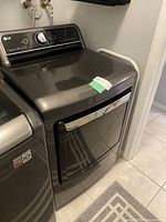 Front and top view of charcoal-gray LG front-load dryer with control panel and round door.