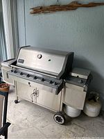 Front side of Weber BBQ grill showing knobs, lid, and wheels.