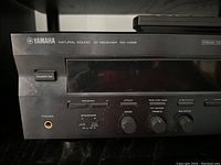 Front left section of Yamaha RX-V596 receiver showing model, standby/on button, headphone jack, program, effect dial, bass, treble, and balance knobs.