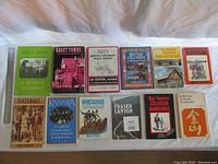 Photo showing 12 books laid out in a single row, cover front facing up to display titles related to British Columbia history and regional stories.