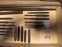 Top view of various vintage punches arranged on a white surface showing different sizes and brands including Proto.