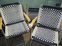 Front view of two chairs showing black and white woven fabric seats and backs with aluminum frames and wooden armrests.