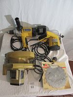 Full view of the three power tools together on white cloth background showing corded drill, circular saw, and tile saw.