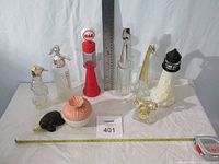 Photo showing nine Avon collectable bottles of varied shapes including seahorse, gas pump, giraffe, lighthouse, dog, and flower styles with ruler for scale.