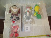 Top-down photo showing all 4 plush toys in sealed plastic bags with a ruler for scale.