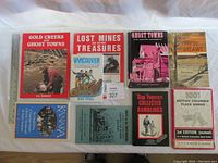 Top-down view of 9 books laid flat, showing covers and titles related to BC history, ghost towns, mining, and place names.