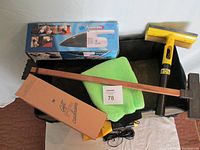 Overview of the car accessory items including the power vacuum in box, folding trunk caddy, green foam heated seat cover, wooden brush, and ice scraper.