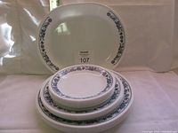 Stacked plates and serving platter showing blue floral pattern on white glassware.