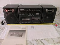 Front view of Panasonic RX-CS710 stereo with speakers and original manual displayed on marble surface, ruler for scale.