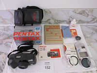 Complete lot showing Pentax Zoom 90 DW film camera accessories including case, manuals, lens cap, filters, and cleaning items.