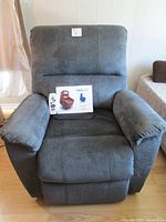 Full front view of grey-tone Therapedic power lift recliner chair with manual on seat