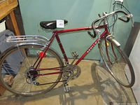 Full side view of vintage ladies Apollo Capri 10-speed bike showing red frame, rear rack, pedals, and tires.