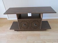 Faux-wood stereo cabinet with open shelf and dual doors with round handles, showing overall structure and dimensions.