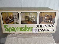 Photo of the original packaging box showing the Spacemaker metal shelving with staged images of the shelving unit in use and branding.