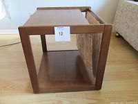 Side view of solid wood side table showing bottom shelf and fabric magazine slot.