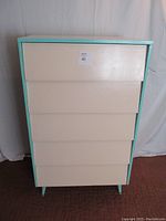Front view of the painted plywood 5-drawer dresser with turquoise trim on edges and legs.