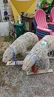Two white wicker polar bear Christmas decorations outside near stacked pink chairs and a green trash bin, showing full sides and front views.