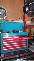 Full view of teal Craftsman metal tool chest with multiple drawers open showing tools inside and on top.