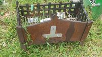 Metal fire pit photographed outdoors on grass showing rectangular shape, lattice sides, and rusted end panels.