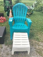 Blue plastic garden chair with a white plastic ottoman in front on a grassy outdoor area.