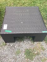Top view of the dark brown faux rattan square garden table on grass and gravel ground.